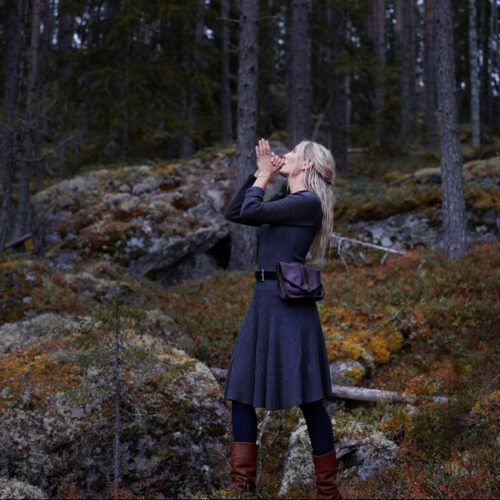 a woman wearing a Handcrafted brown Nordic leather bag made from vegetable-tanned leather.