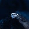 Sterling silver Goddess Ring with an elegant pointed silhouette, intricate engraved details, and a hidden butterfly motif laying on a dark rock