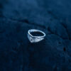 Sterling silver Goddess Ring with an elegant pointed silhouette, intricate engraved details, and a hidden butterfly motif laying on a dark rock