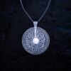Sterling silver shield pendant with engraved Nordic runes on a silver chain against a dark background