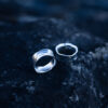 Two handcrafted sterling silver water rings with flowing organic curves inspired by waves laying on a rock