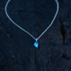 Nebula Necklace with a deep blue Swarovski crystal pendant on a sterling silver chain laying on a rock