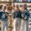 3 smiling women holding handmade ceramic mugs in a shop, featuring an ice-inspired glaze and textured surface inspired by Nordic winter landscapes