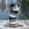 3 handmade ceramic mugs, “Singing Ice” by Jonna Jinton stacked on top of each other, featuring an ice-inspired glaze and textured surface inspired by Nordic winter landscapes.